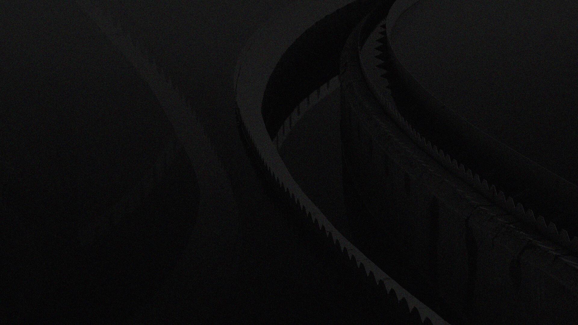 Close-up of a dark, abstract spiral structure with jagged edges, creating a sense of depth and mystery against a black background.