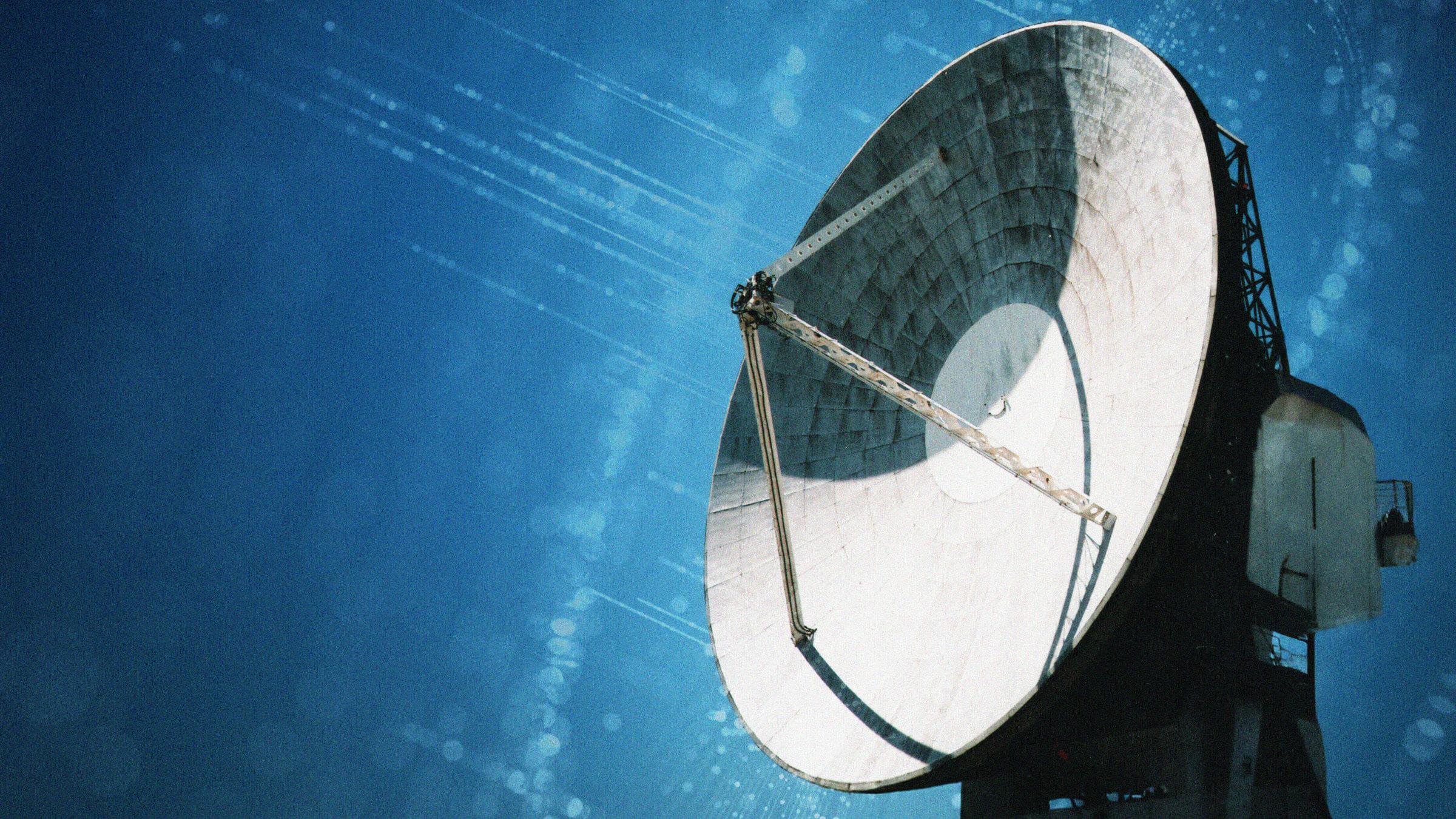 Large satellite dish against a clear blue sky, with sunlight reflecting off its surface, capturing a sense of communication and technology.